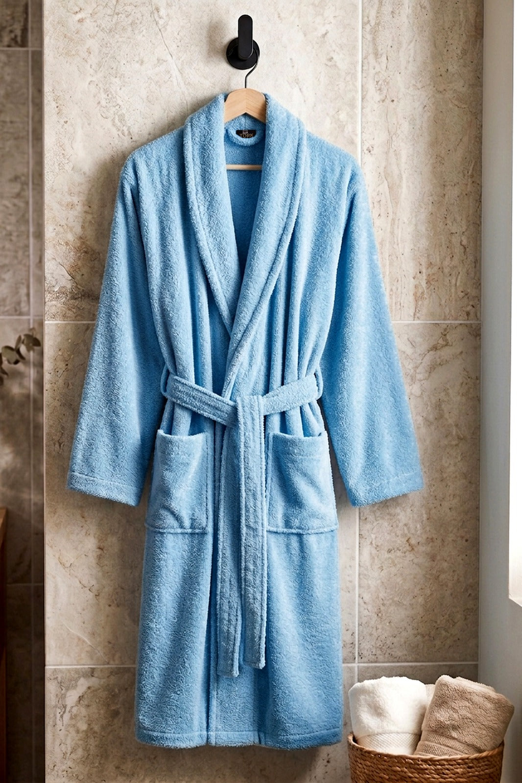 TORK cotton Turkish bathrobe hanging on a wooden hook, soft and plush fabric, beige color, cozy and comfortable for lounging.